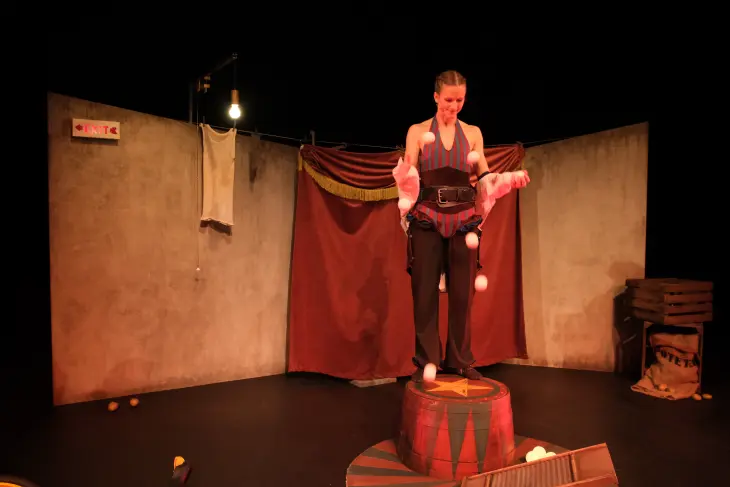 Circus Antero kvinnelig sjonglør på toppen av en pidestall med lysende kuler i lufta foran